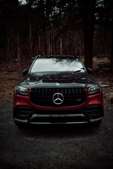 Front view of a luxury SUV parked in a dark, wooded area, conveying elegance and power.