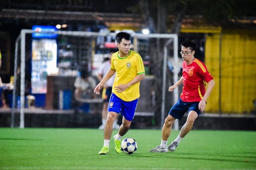 Two young men play soccer passionately on a lit field in Hanoi, Vietnam.