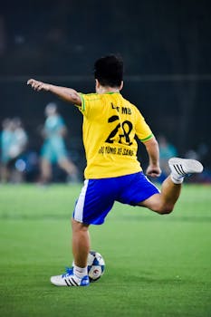 Soccer player kicks ball on field at night in Hà Nội, Việt Nam.
