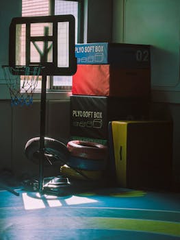 Dimly lit indoor gym with basketball hoop and exercise equipment, creating a moody athletic atmosphere.