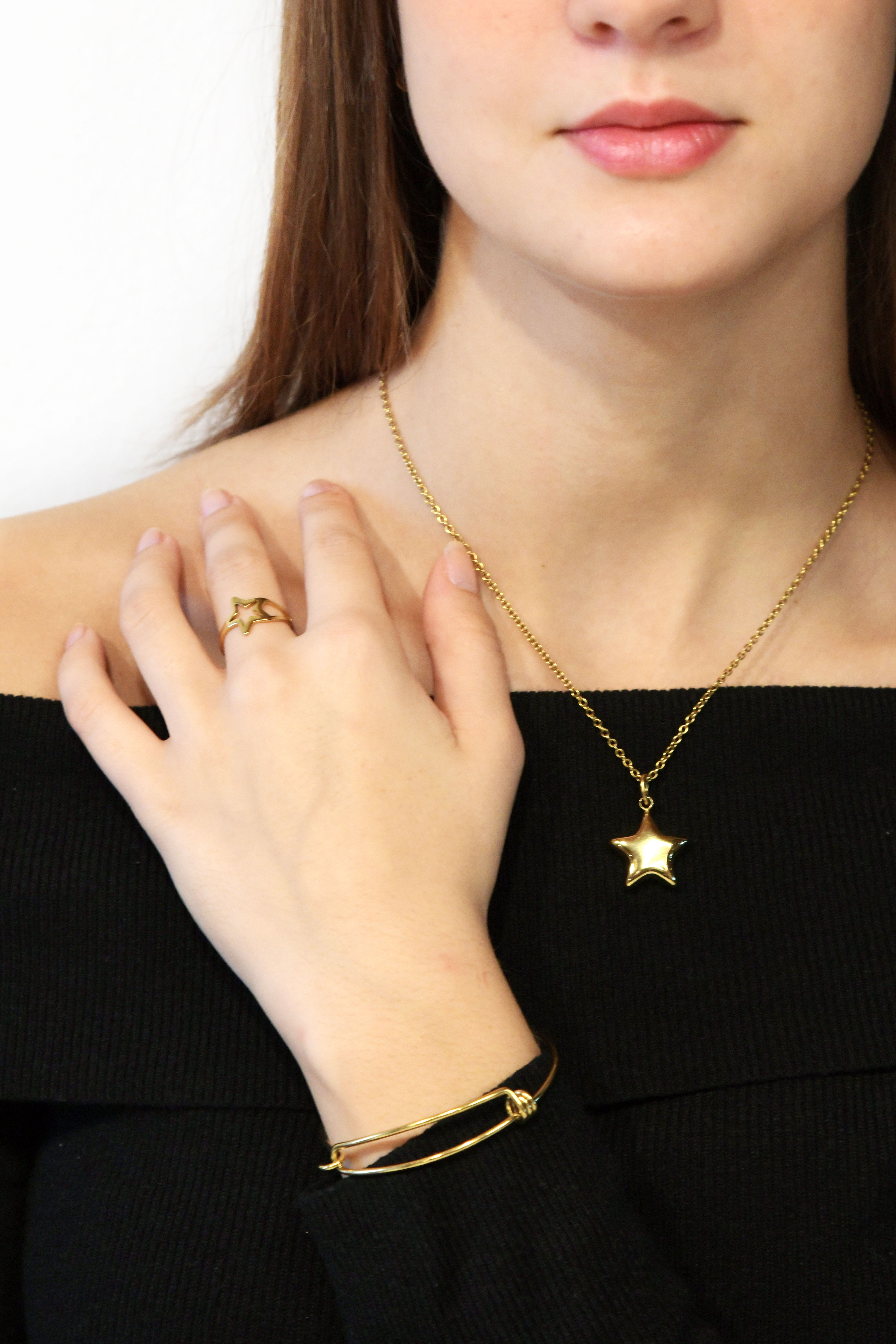 Fotomural Primer plano de una mujer que luce elegantes joyas de oro, incluido un collar de estrellas, un anillo y una pulsera.