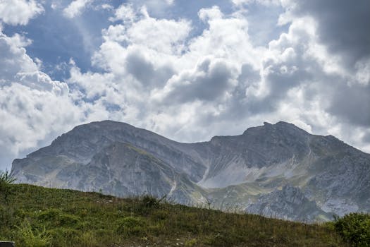 Scenic view of a majestic mountain under a sky filled with dramatic clouds, creating a breathtaking natural scene.