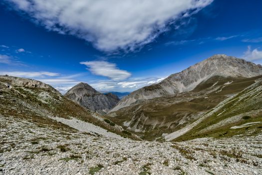 A stunning view of a rocky mountain landscape under a vibrant blue sky with dramatic clouds.