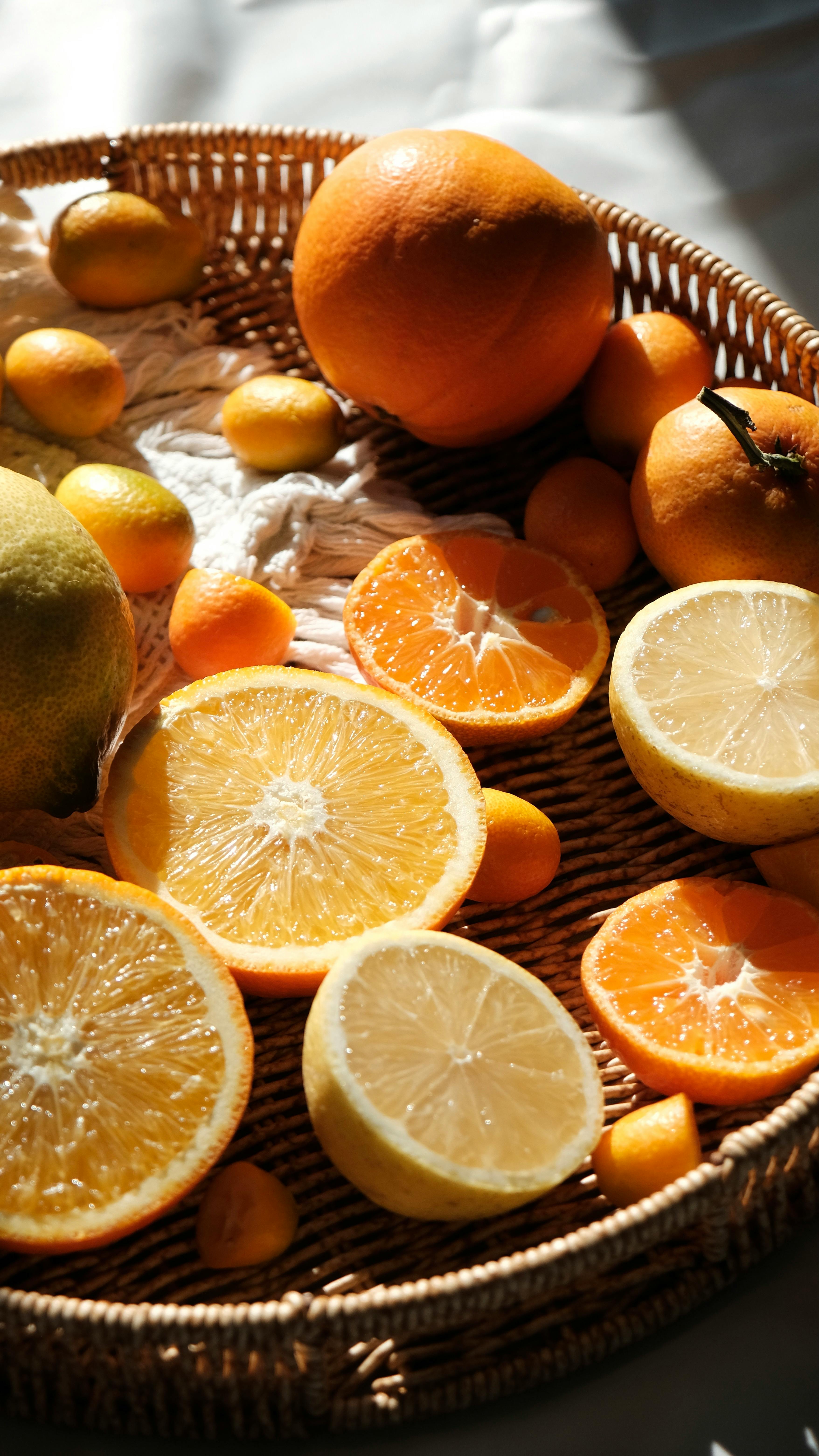 Vibrant oranges and lemons in a wicker basket, beautifully lit by sunlight.