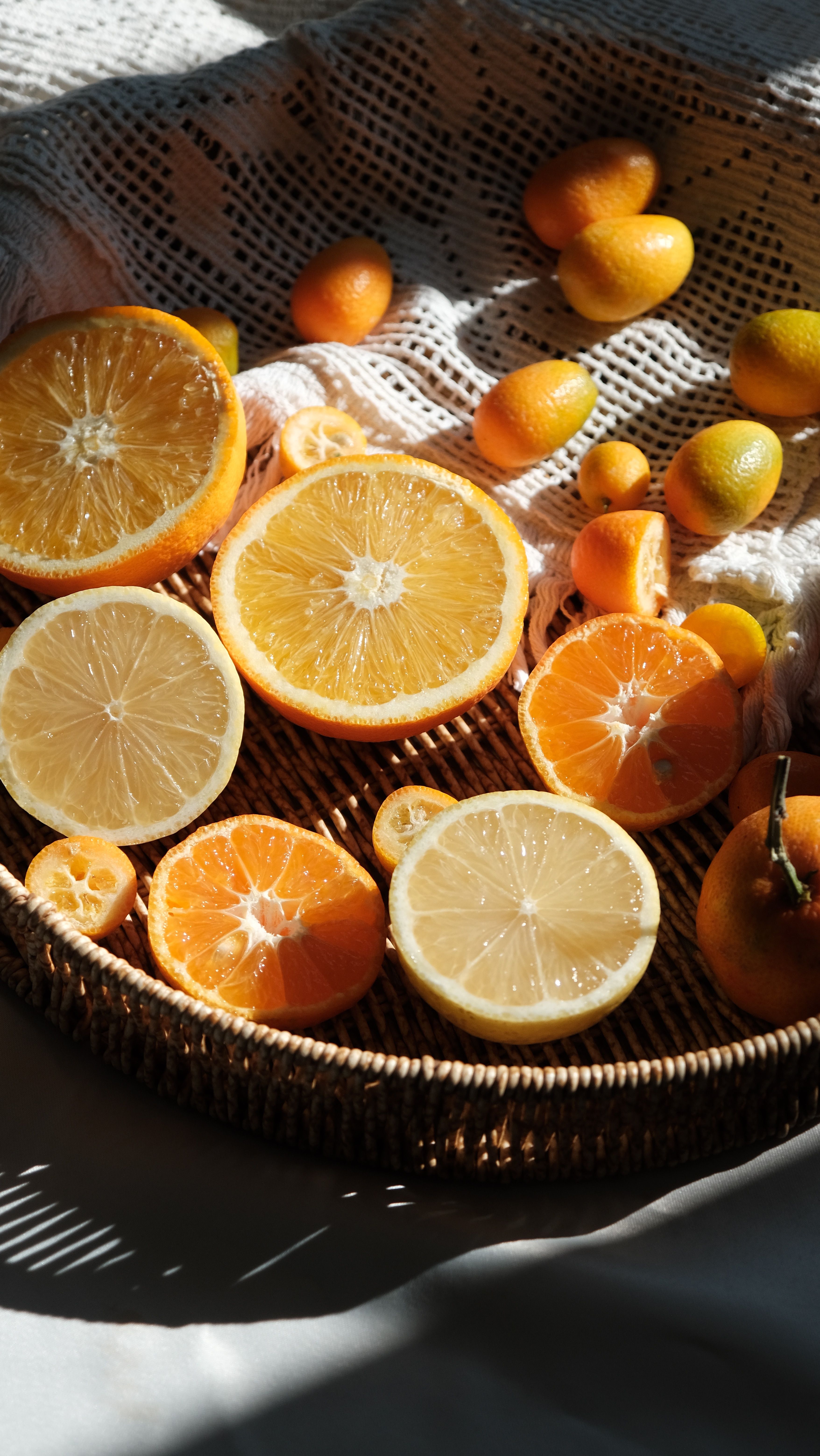 Sliced oranges and lemons on rattan tray with shadow play.