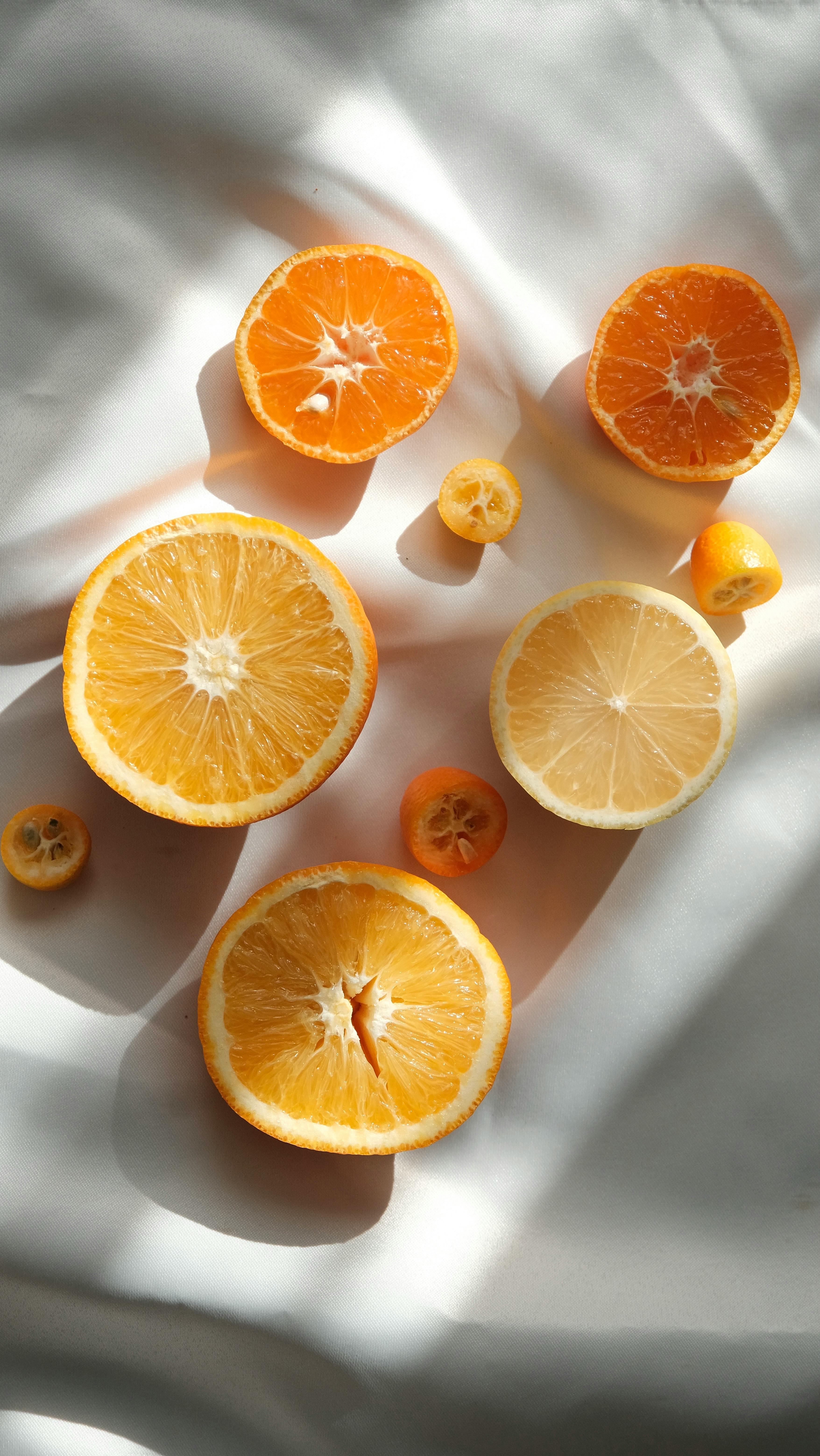 Slices of various citrus fruits on a white surface with soft sunlight and shadows, creating a fresh and vibrant look.