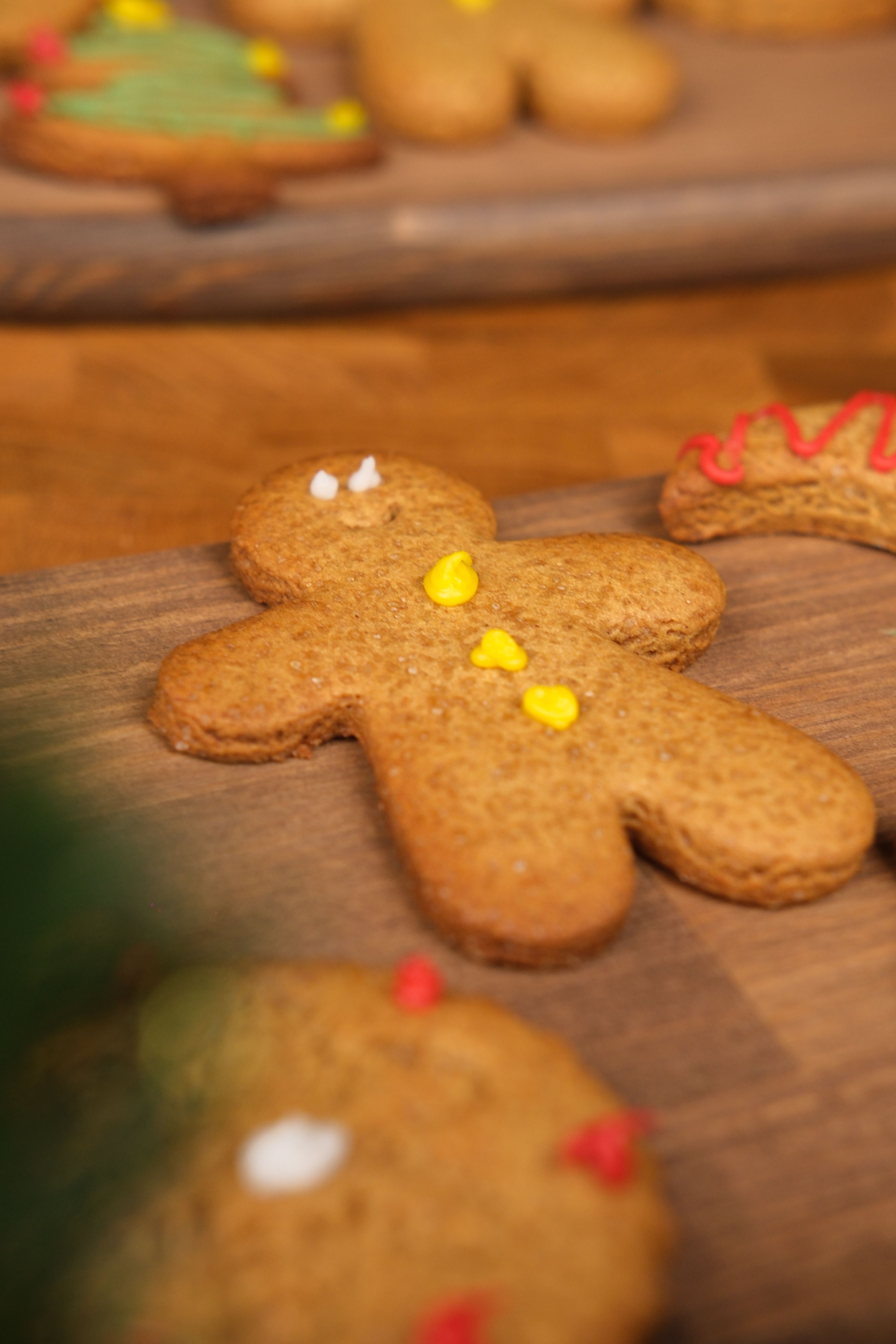 Close-up of decorated gingerbread cookies featuring a classic gingerbread man on a wooden background.