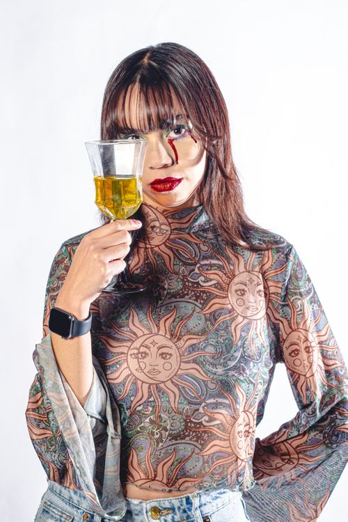 Free A woman with artistic makeup holding a wine glass against a white background, showcasing fashion and creativity. Stock Photo