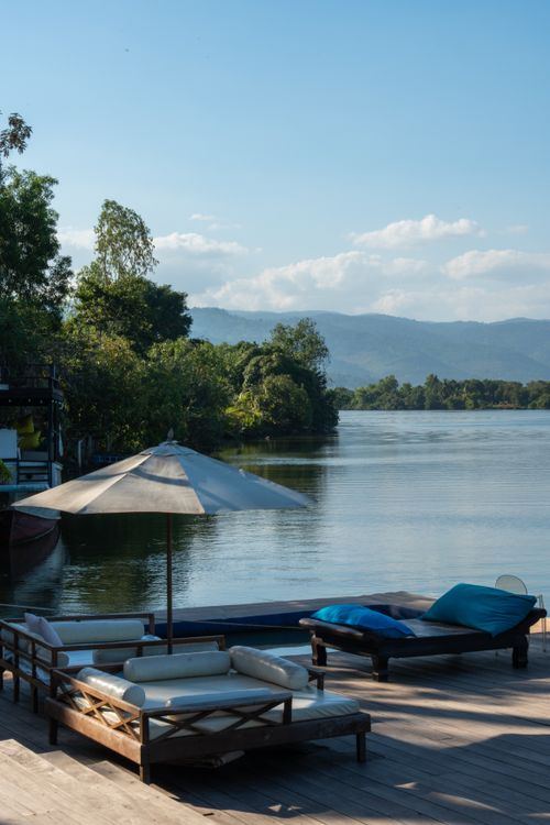 Tranquil Riverside Deck with Lounge Chairs and Umbrella · Free Stock Photo