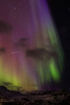 Breathtaking northern lights illuminating the night sky with vibrant colors over a snowy mountain terrain.
