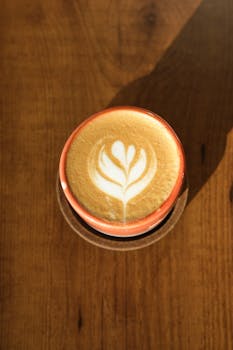 Top view of a cappuccino with elegant latte art on a sunny wooden table in Istanbul.