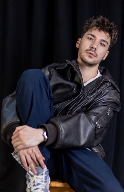 Free Stylish young man in a leather jacket posing casually indoors. Stock Photo