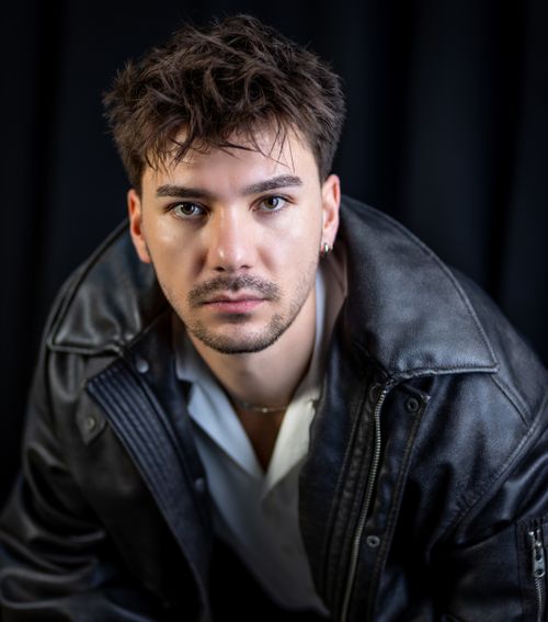 Free Close-up portrait of a young man wearing a leather jacket with a focused expression. Stock Photo