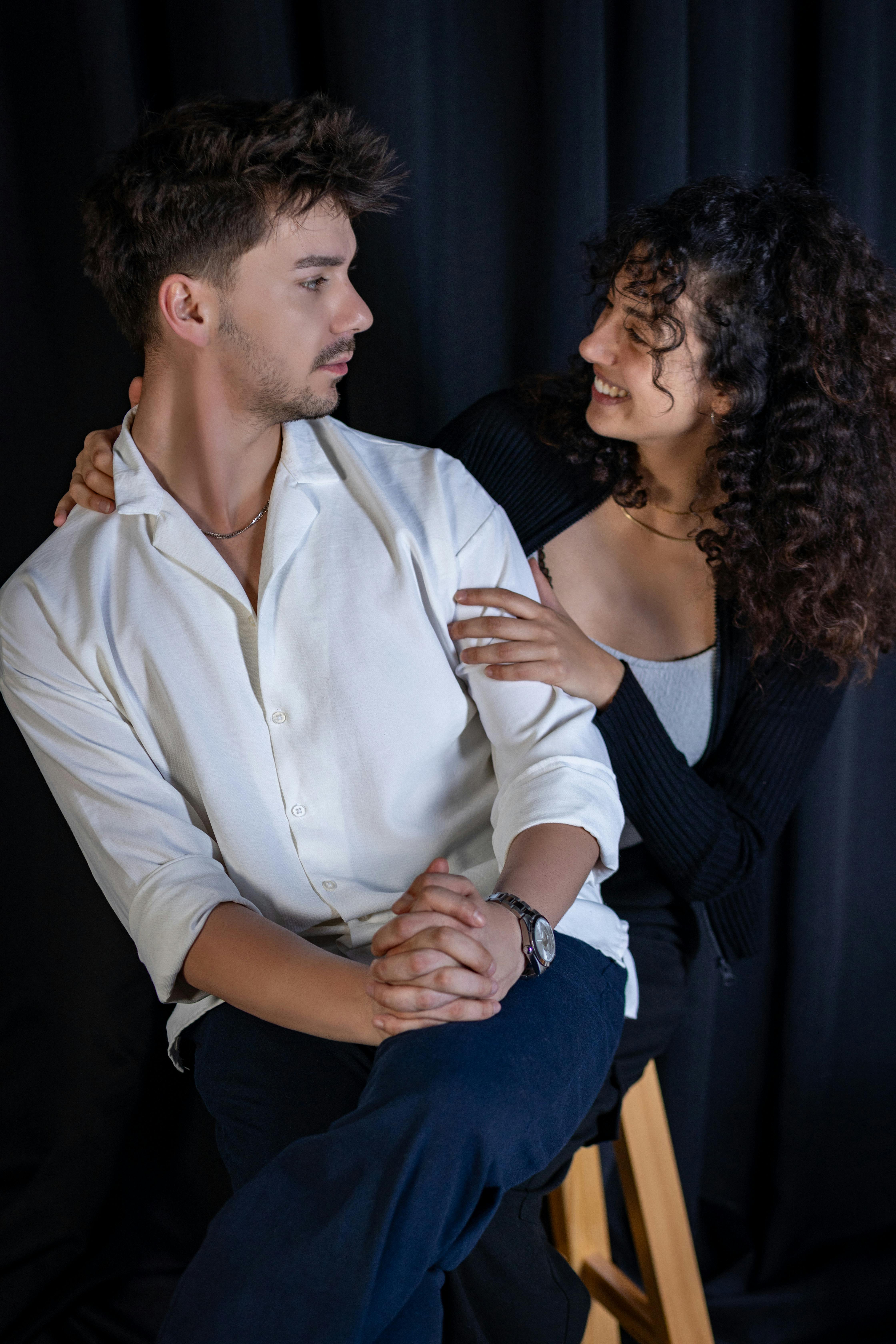 A couple in love sharing a joyful moment against a dark background.