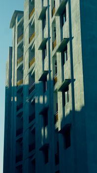 Side view of a tall urban building with striking shadows and clear blue sky.