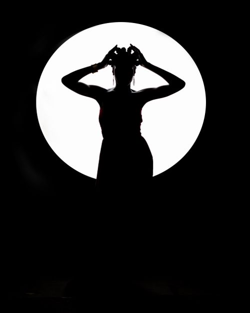 Free Artistic silhouette of a female dancer posing against a bright spotlight, creating dramatic contrast. Stock Photo