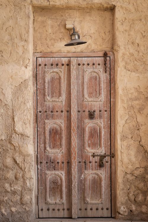 Free A vintage wooden door mounted on a textured stone wall with rustic charm and architectural detail. Stock Photo