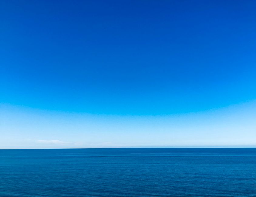 A serene view of the vast blue ocean meeting a clear blue sky, showcasing nature's tranquil beauty