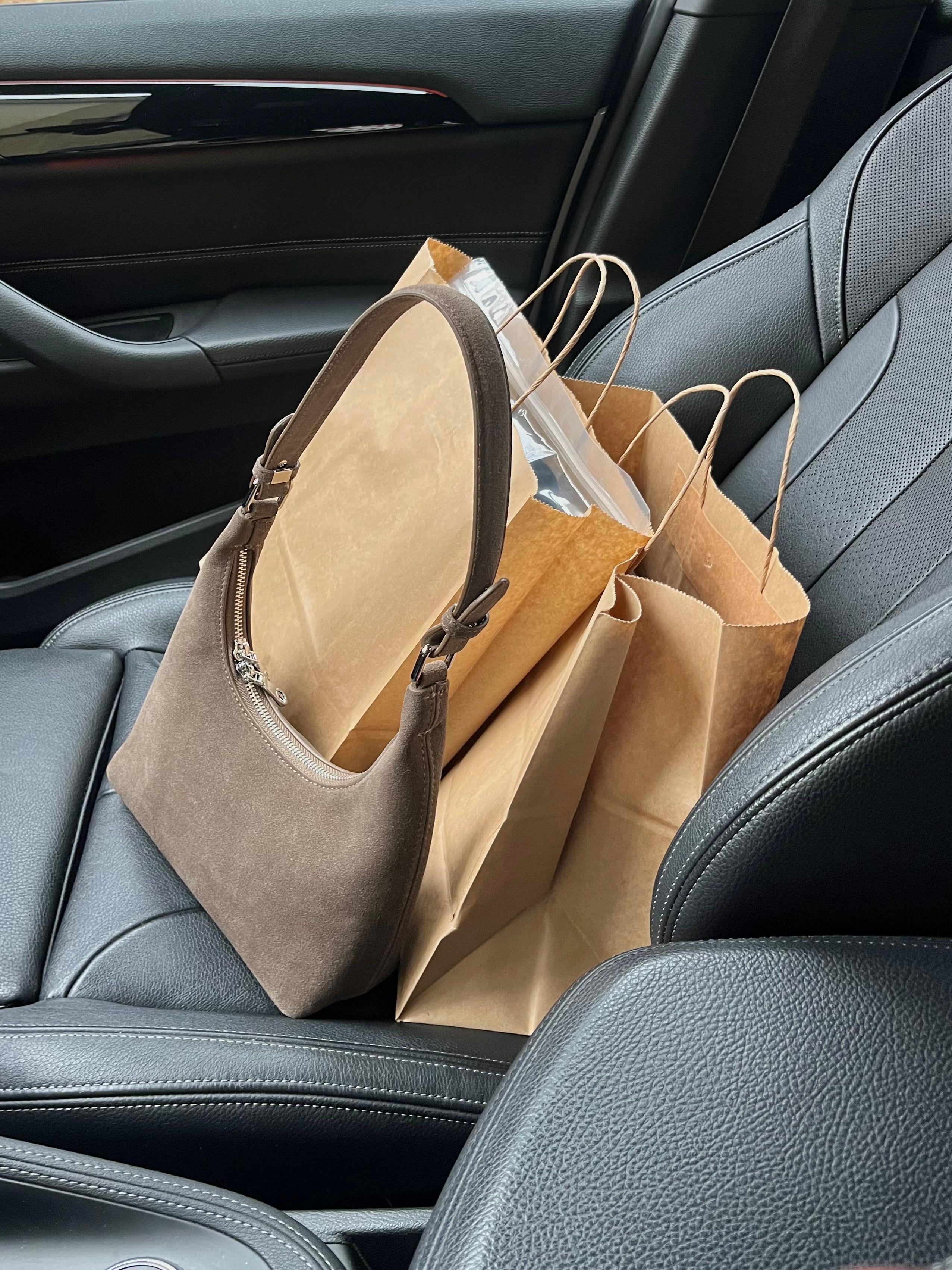 Chic shopping bags and leather purse on car seat, capturing modern retail therapy and lifestyle elegance.