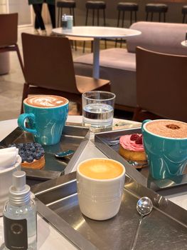 Cozy cafe setting featuring cappuccino, latte, and desserts on modern trays, perfect for a relaxing break.
