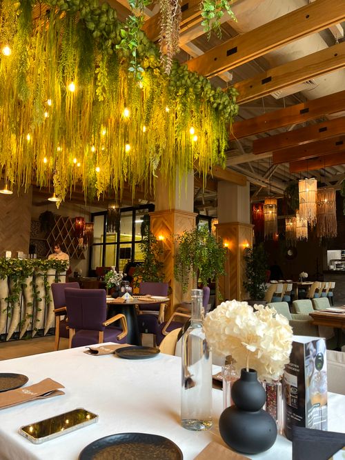 Free A chic restaurant interior featuring vibrant greenery and warm lighting, ideal for upscale dining. Stock Photo