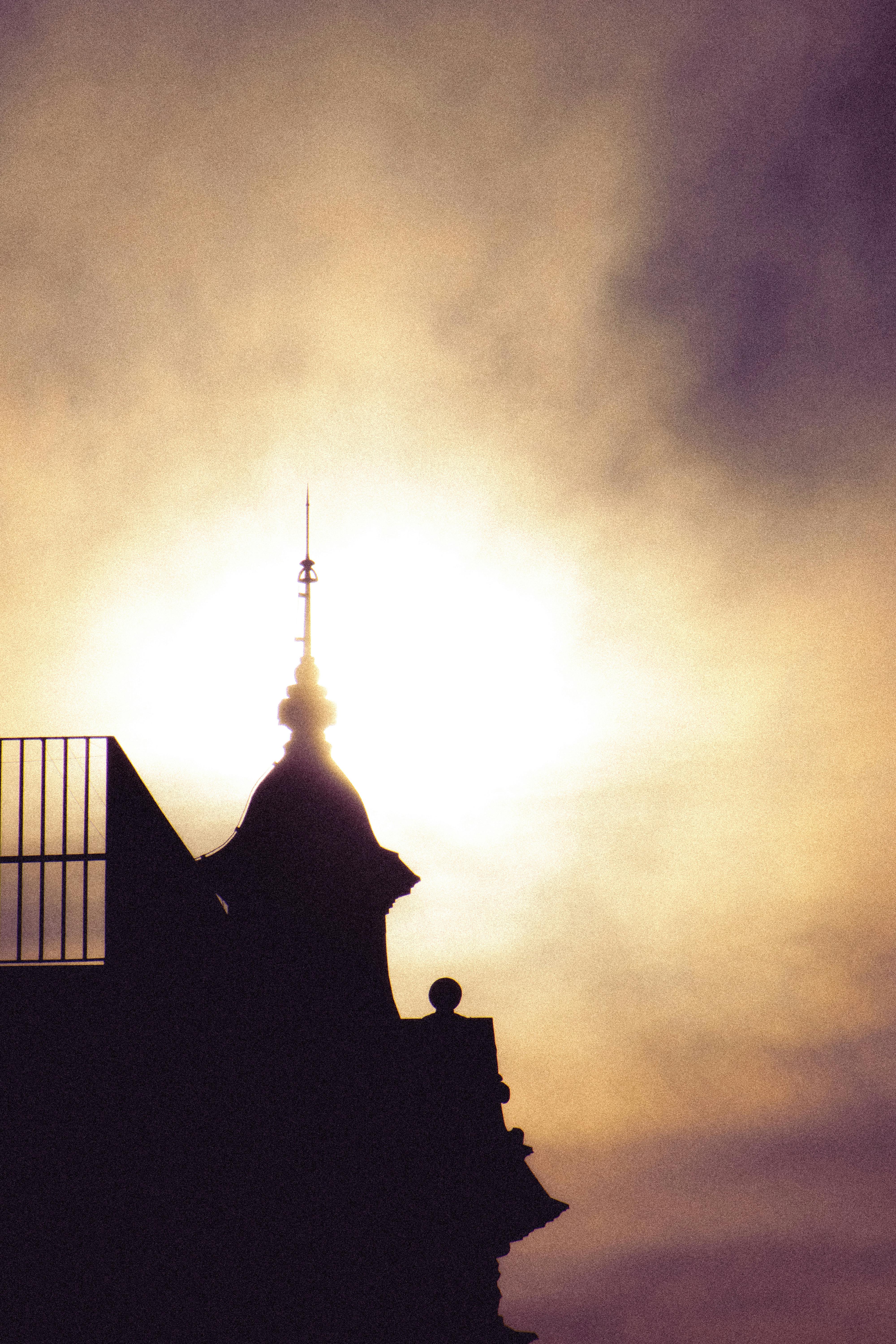 Silhouette of a decorative tower with intricate design against a hazy sky.