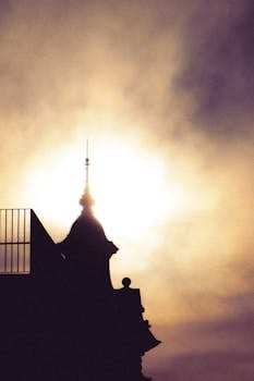 Silhouette of a decorative tower with intricate design against a hazy sky.