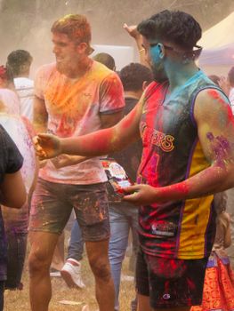 Vibrant Holi festival celebration in Melbourne with people covered in colorful powders.