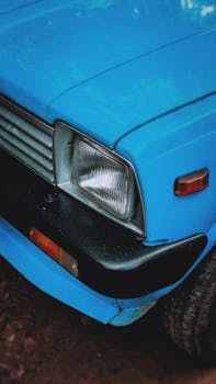 A detailed close-up of a vintage blue car's front corner in Kerala, India.
