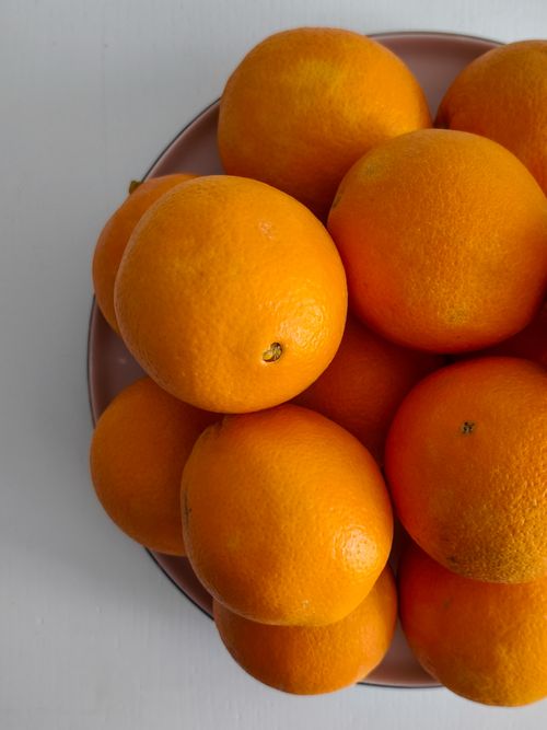 Free Top view of a bunch of fresh oranges in a pink bowl on a white table. Stock Photo