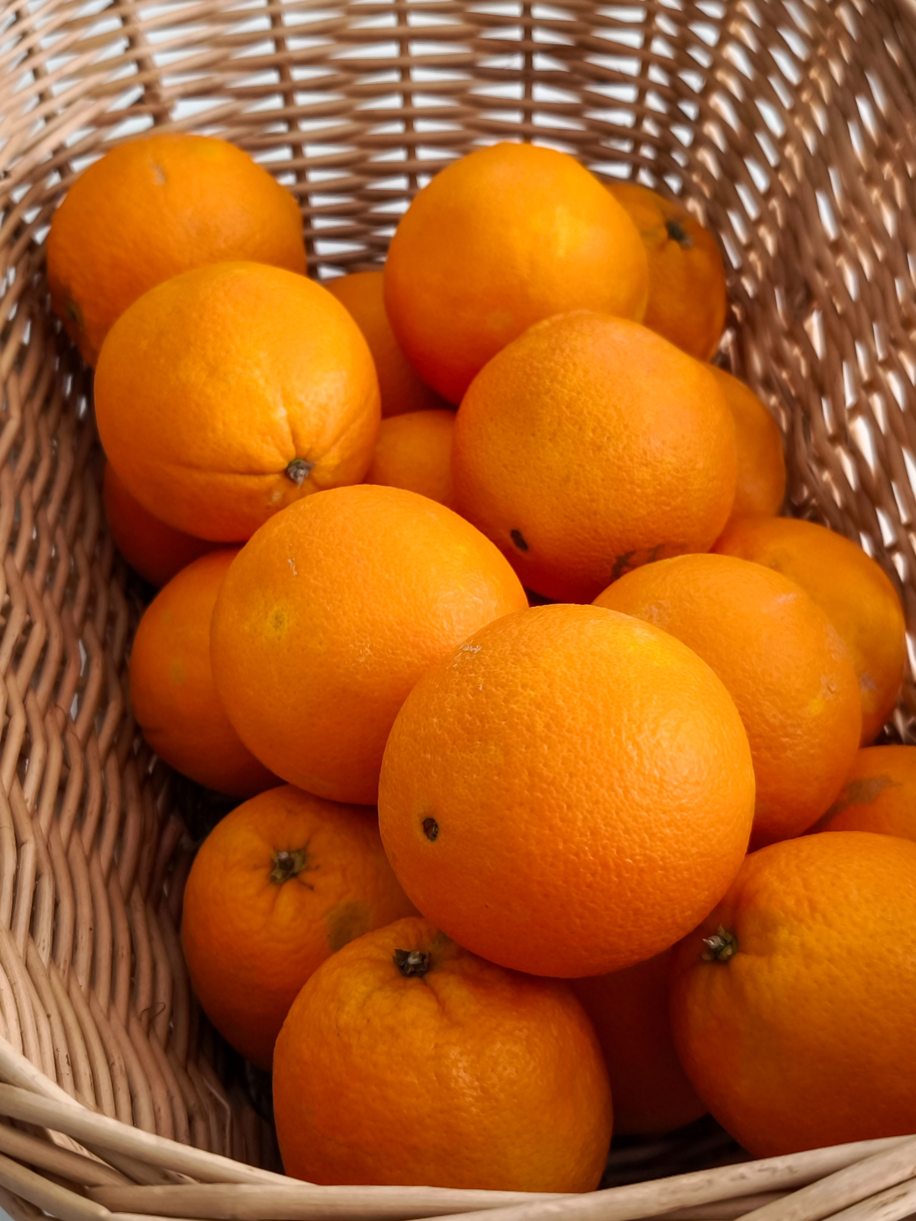 A collection of vibrant, juicy oranges in a rustic wicker basket, ideal for fresh and healthy lifestyle themes.