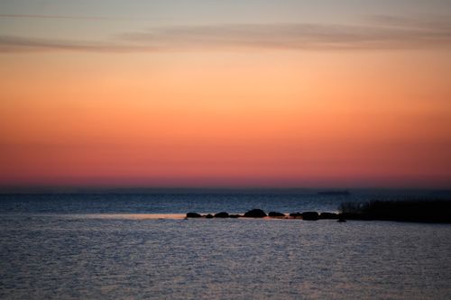 Free A tranquil sunset view over the ocean with a soft gradient sky and calm waters. Stock Photo