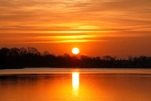 Breathtaking sunset with vibrant orange hues reflecting over a serene lake.