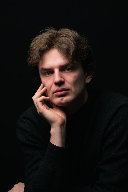 Free A contemplative man posing against a dark backdrop, creating a dramatic and moody portrait. Stock Photo