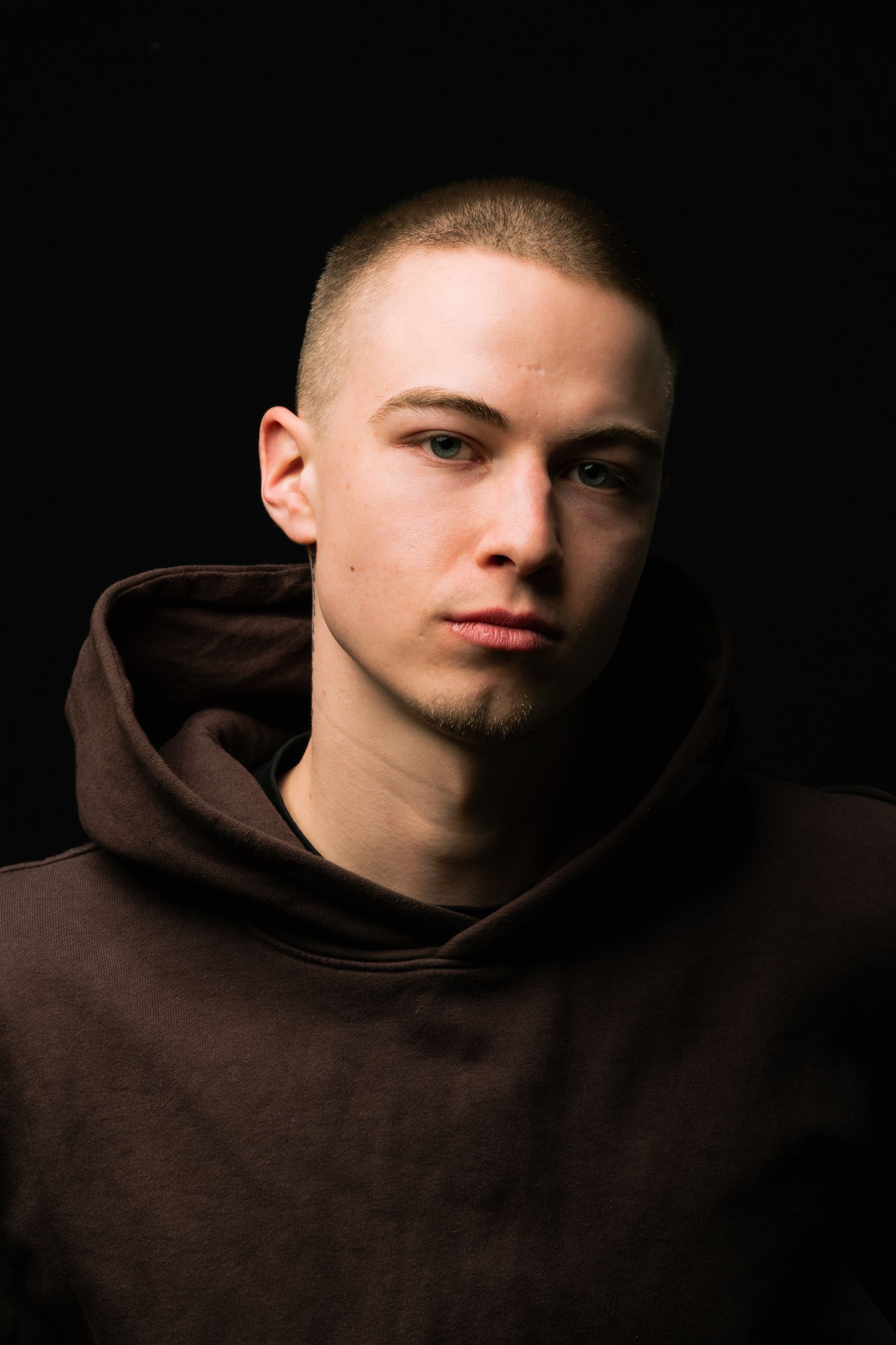 Close-up portrait of a young man in dramatic lighting, emphasizing deep shadows.