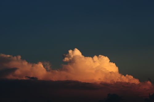 Free Vivid sunset clouds with a dramatic sky, showcasing deep orange hues under a darkening blue sky. Stock Photo