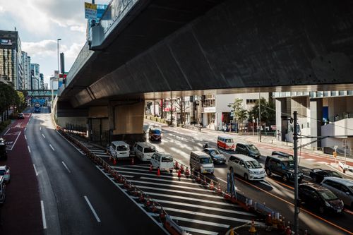 Free A bustling urban street scene with cars under a highway overpass in daylight. Stock Photo
