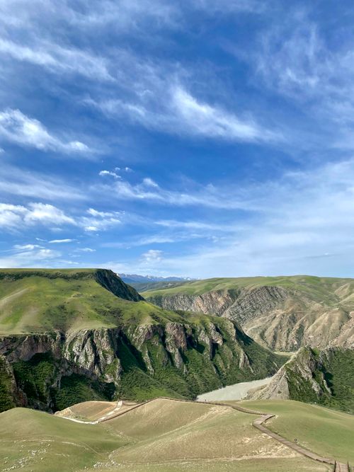 Free Breathtaking view of lush green mountains under a vibrant blue sky in Xinjiang. Stock Photo