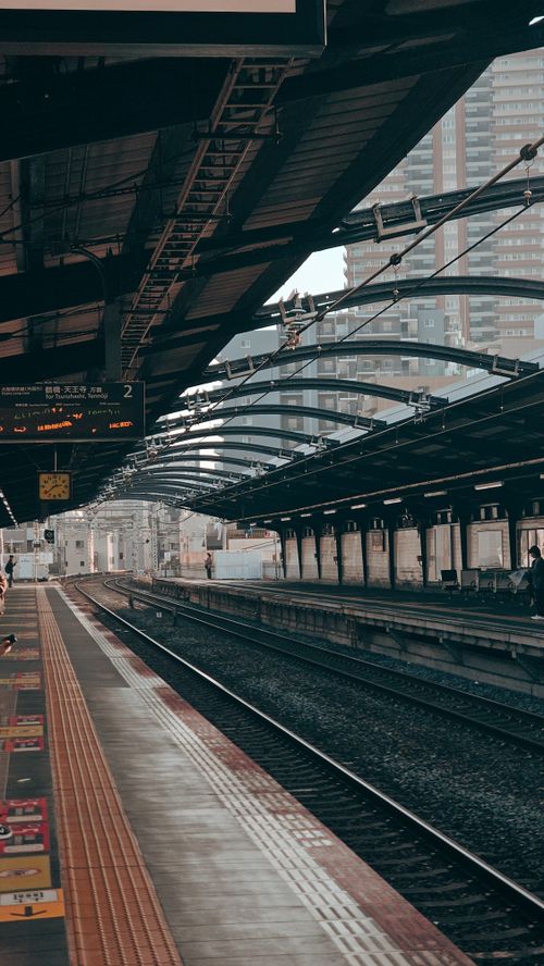 Free Empty urban train station with overhead structures and city buildings in the background. Stock Photo