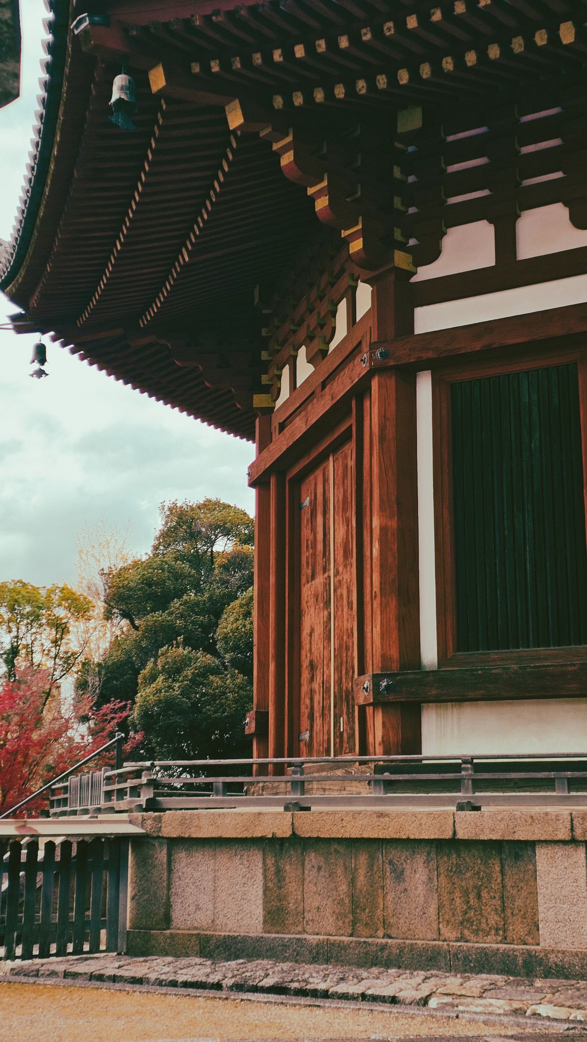 Traditional Japanese temple building with wooden architectural details surrounded by lush greenery