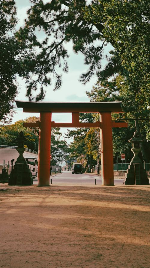 Free A tranquil scene featuring a traditional Japanese Torii gate surrounded by lush greenery under a clear sky. Stock Photo