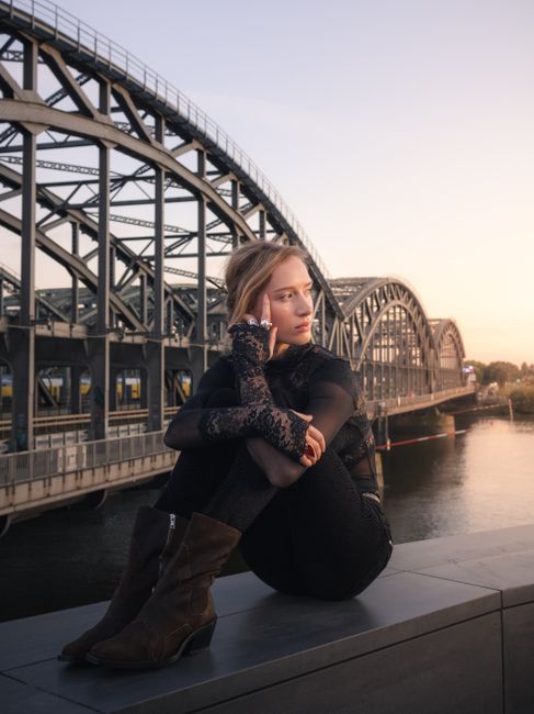 A thoughtful woman sits by the Hamburg bridge at twilight, capturing the serene atmosphere of the city.