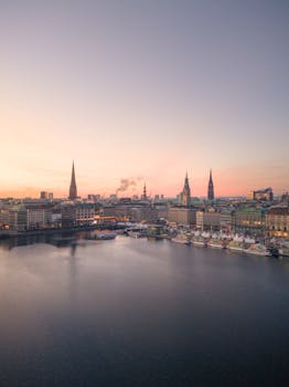 Aerial view of Hamburg skyline and Alster Lake at sunset with vivid colors and iconic spires.