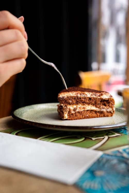 Free A delectable slice of tiramisu being served in a quaint cafe, perfect for dessert lovers. Stock Photo