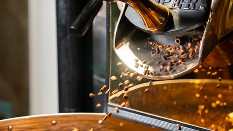 Close-up of coffee beans roasting in a professional coffee roaster machine.