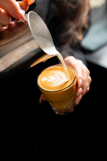 A glass mug of breve showing a dense, ivory-colored microfoam layer sitting on top of a rich, cream-colored espresso drink.