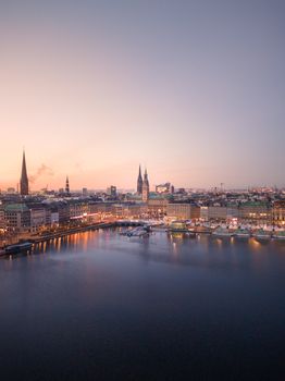 Stunning aerial view of Hamburg skyline with iconic landmarks at sunset, reflecting over the water.