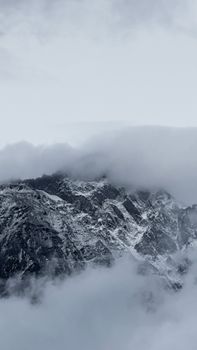 Snow-covered mountains shrouded in mist, creating an ethereal landscape in Stepantsminda, Georgia.