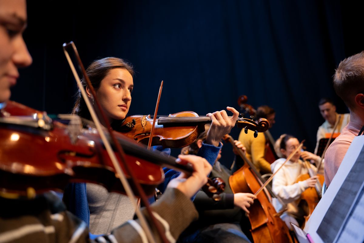 Sectiune de coarde a unei orchestre, cu violonista in prim-plan