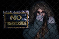 Woman Behind Black Chainlink Fence With No Trespassing Signage
